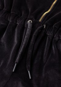 Mustast sametist kangas, millel on hõbedaste silmuste kaudu läbipunutud nöör ja kuldne lukk kogutud vöörihmaga.