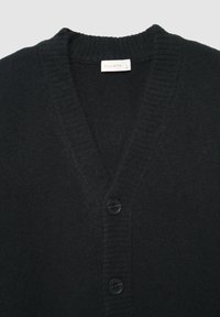 Schwarze V-Ausschnitt-Strickjacke aus weichem Strickmaterial, mit gerippten Abschlüssen und drei schwarzen Knöpfen vorne. Das Etikett trägt die Aufschrift "CALLIOPE."