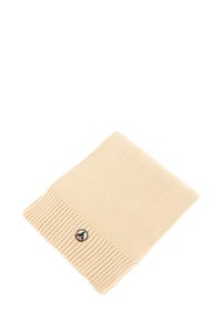 Bonnet en tricot beige clair avec un revers côtelé. Présente un patch rond noir et rouge à l'avant. Texture douce et épaisseur moyenne.