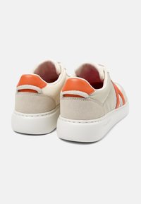 Sneakers med en krämfärgad ovandel, orange läderdetaljer och en tan mockahäl. Har en vit gummisula och en minimalistisk design.