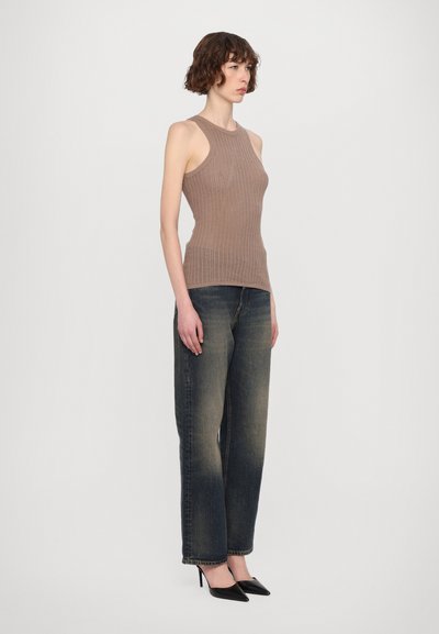 Brun ribbet tanktop med en tettsittende silhuett, kombinert med mørkeblå løstsittende jeans og svarte spisse hæler. Glatt tekstur og minimalistisk design.