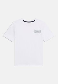 Λευκό κοντομάνικο μπλουζάκι με μικρό ορθογώνιο λογότυπο "GUESS" στο πάνω αριστερό μέρος του στήθους.