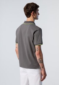 Polo grigio a maniche corte con vestibilità slim, con colletto e piping verde brillante lungo il collo e i bordi delle maniche.