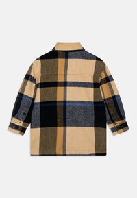 Koszula w kratę w kolorze beżowym, czarnym, granatowym i szarym. Posiada kołnierz, długie rękawy, mankiety na guziki oraz prosty dół z lekko teksturowanej tkaniny.