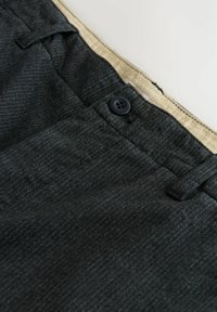 Dark gray pinstriped trousers with a black button and beige inner waistband stitching detail.