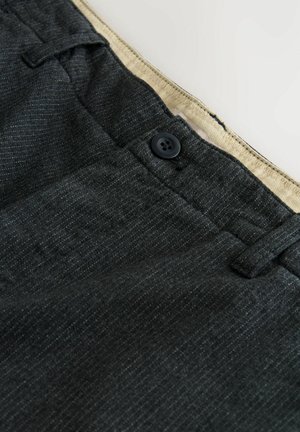 Dunkelgraue, gestreifte Hose mit einem schwarzen Knopf und beiger Innengurtnaht.