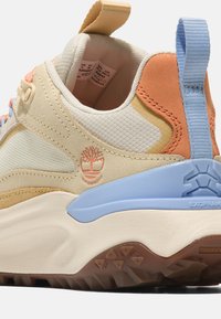 Beige och orange sneakers i textil och läder, med en blå detalj, gummisula och vattentät logotyp. Snörning och dragflik ingår.
