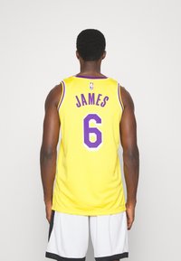 Gul baskettröja med lila accenter, texten "JAMES" och nummer "6" på ryggen, med mesh-struktur och en avslappnad passform.