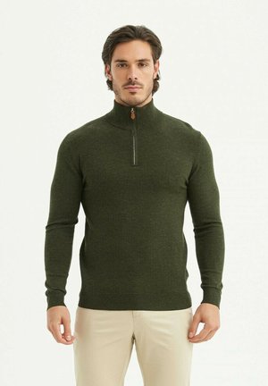 Pull vert à col zippé fabriqué en tissu doux, avec des manches longues, des poignets côtelés et une texture lisse. Agrémenté d'un zip marron.