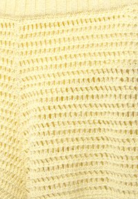 Gelbes gestricktes Gewebe mit einem lockeren, offenen Webmuster. Die Textur ist weich und zeigt abwechselnd feste und Netzabschnitte.
