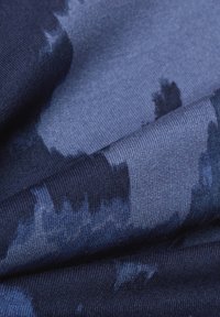 Marineblauwe stof met een gestructureerde brei en abstract lichtblauw patroon, met een zachte val en lichte glans, ideaal voor kleding.