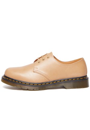 Beige Leder-Schuh mit runder Zehenpartie, fünf Ösen-Schnürung und kontrastierendem gelben Nähten. Schwarze Gummisohle mit gerippter Struktur.