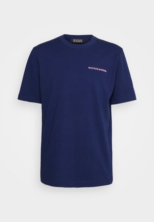 T-shirt en coton bleu marine à manches courtes, col rond, avec un petit logo "SCOTCH & SODA" rose sur la poitrine gauche. Texture lisse, coupe régulière.