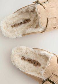 Bottines en simili-suède beige avec une doublure douce et fourrée. Équipées d'une sangle à boucle et d'une semelle intérieure rembourrée pour plus de confort.