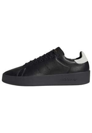 Sort lavtop Adidas-sneaker med tyk sål, perforeret side, sorte snørebånd og hvid hælkappe.