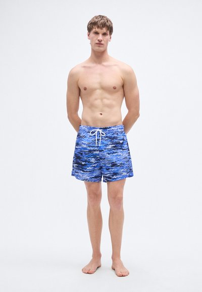 Μπλε μαγιό σορτς με μοτίβο κυμάτων, κατασκευασμένο από ελαφρύ ύφασμα, με ελαστική μέση και ρυθμιζόμενο κορδόνι.