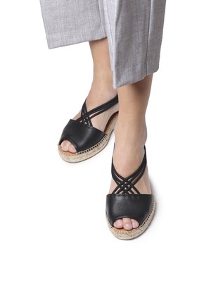 Black leather espadrille sandals with an open toe, featuring crisscross straps and a woven rope sole.||