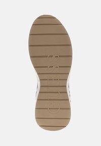 Suola di scarpa in gomma beige con scanalature orizzontali e logo "GUESS" in rilievo vicino al tallone, caratterizzata da una superficie liscia e bordi arrotondati.