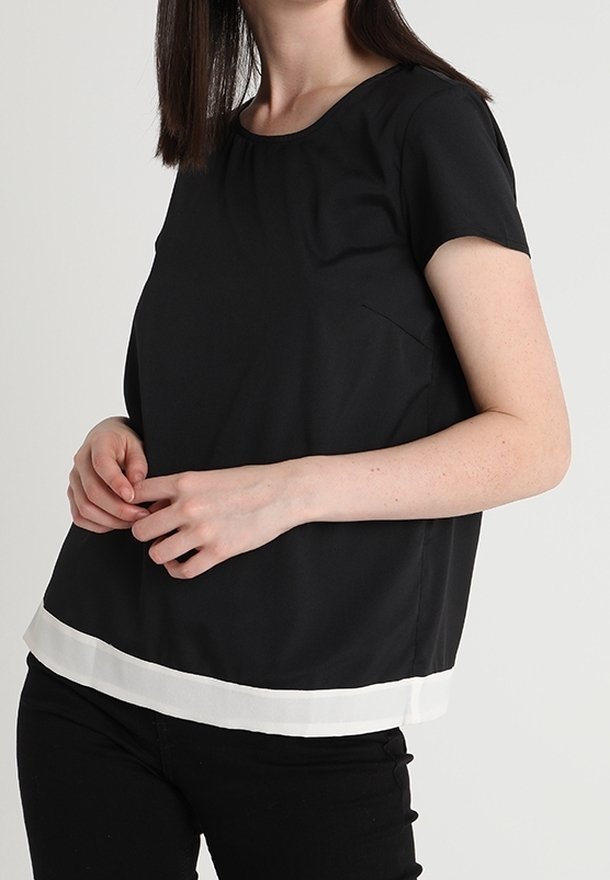 Top nero a maniche corte con scollo rotondo, caratterizzato da un orlo bianco. Tessuto liscio con una silhouette semplice e tasca laterale.