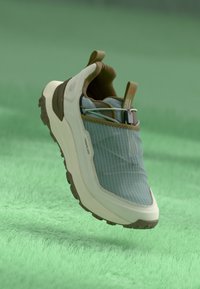 Sneaker with a light blue, striped textile upper, cream-colored sole, and brown accents. Features a heel pull tab and textured outsole.