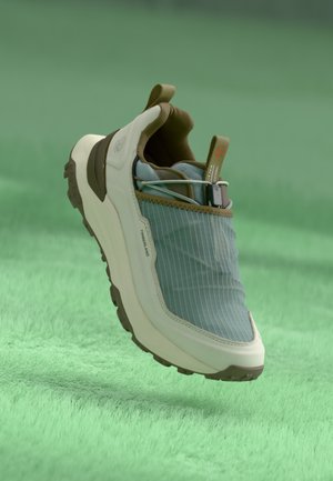 Sneaker met een lichtblauwe, gestreepte textielen bovenkant, crèmekleurige zool en bruine accenten. Bevat een treklus aan de hiel en een stevige loopzool.