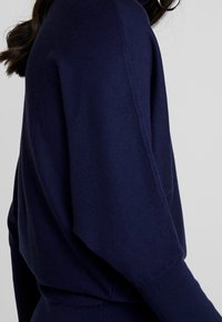 Laivastonsininen neulepaita, jossa on rento istuvuus, lepakkohihat ja ribbaatut hihansuut, valmistettu pehmeästä, teksturoidusta kankaasta.