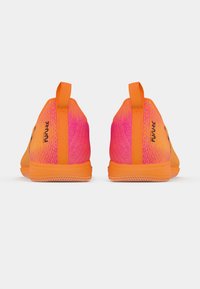 Élénk narancssárga és rózsaszín sportcipők hátulról, huzófülekkel és texturált talpakkal, síma fehér háttér előtt.