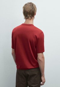 Rød bomulds T-shirt med korte ærmer og rund hals, der har en glat tekstur og et enkelt, udecorated design.