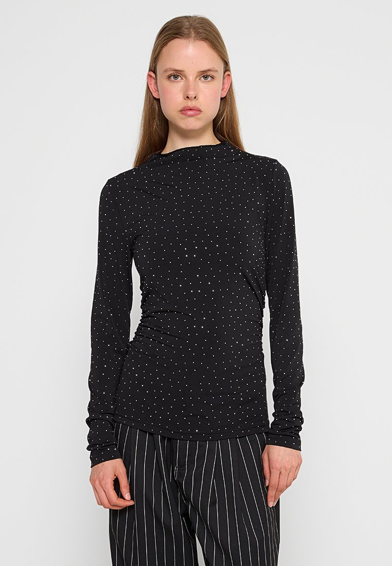Top nero a maniche lunghe realizzato in tessuto leggero, con pois bianchi su tutta la superficie, dal design aderente e con collo alto.