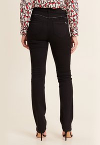 Jeans skinny neri con vita alta, caratterizzati da dettagli di cucitura sottili sulle tasche posteriori e da una texture liscia e raffinata.