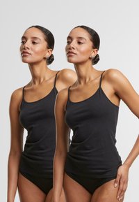 Black cotton camisole with thin straps, featuring a fitted design and smooth texture, shown on two models in a neutral background.