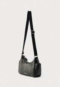 Μαύρο υφασμάτινο τσάντα ώμου με υφή καπιτονέ, ρυθμιζόμενο λουράκι και ασημένιες μεταλλικές λεπτομέρειες. Διαθέτει κλείσιμο με φερμουάρ και λεπτομέρεια λογοτύπου.