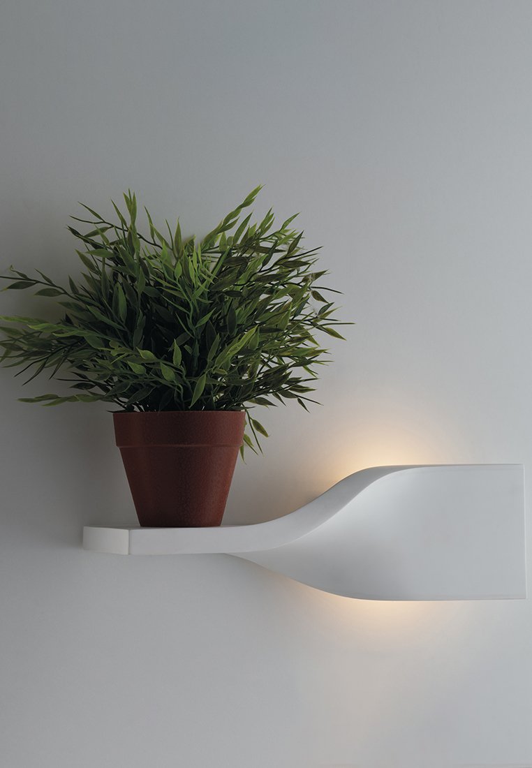 Weißes, wandmontiertes Regal mit geschwungenem Design, das einen braunen Terrakottatopf mit grünen Pflanzen unterstützt, mit sanftem Licht im Hintergrund.