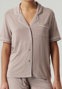 Koszula nocna z krótkim rękawem w jasnobrązowym kolorze, z kieszonką, białym wykończeniem wzdłuż kołnierzyka i listwy guzikowej oraz zapięciem na guziki. Miękka, lekka tkanina.