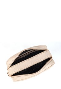 Béžová kožená taška s několika zipovými přihrádkami, černý interiér s puntíky a hladkou texturou. Obsahuje detaily ve zlatém odstínu.