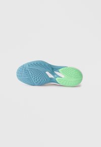 Sola di una scarpa sportiva con battistrada blu strutturato nella parte anteriore e battistrada verde nel tallone, progettata per aderenza e flessibilità su uno sfondo bianco.