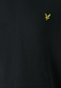 Hanorac negru cu o texturămoale, având un mic logo brodat cu o vultur galben pe piept. Design clasic cu gât rotund.