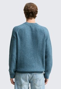 Niebieski sweter prążkowany z długimi rękawami i okrągłym dekoltem. Wykonany z teksturowanej tkaniny, o luźnym kroju i prostym dole.