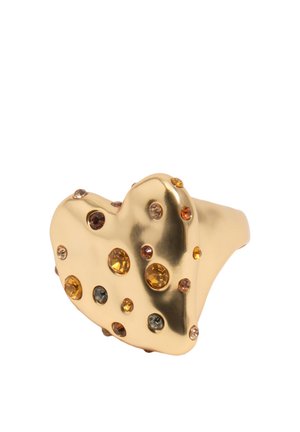 Złoty pierścionek w kształcie serca ozdobiony małymi, okrągłymi kamieniami szlachetnymi w kolorach bursztynowym, brązowym i szarym, z polerowaną i refleksyjną powierzchnią metalu.