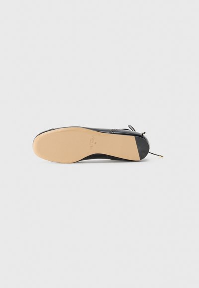 Black patent leather shoe with a rounded toe and thin ankle strap. Beige sole with slight arch and gold-tone hardware detail.