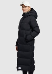 Must have pikk must puffer jope kapuutsiga, lukuga ja küljetaskutega. Omab tikitud osi ning logo paika all.