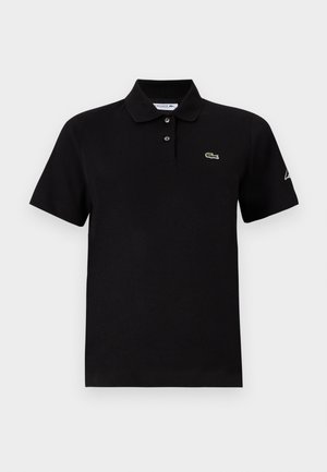 Melns īsroku polo krekls ar divām pogām, apkakli, mazu zaļu krokodila logo uz krūtīm un baltu uzrakstu uz kreisās piedurknes.