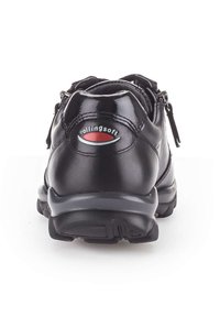 Chaussure en cuir noir avec une finition lisse et brillante, dotée d'un col rembourré, d'une fermeture éclair sur le côté et d'une semelle en caoutchouc noir texturé. Logo de la marque à l'arrière.