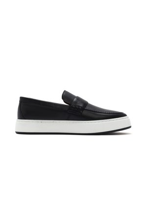 Black leather loafer with white thick rubber sole, slip-on style, and stitched detailing along the upper part of the shoe.