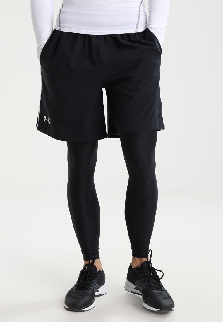Black athletic shorts over black compression leggings, lightweight material, elastic waistband, with reflective logo accents and side pockets.