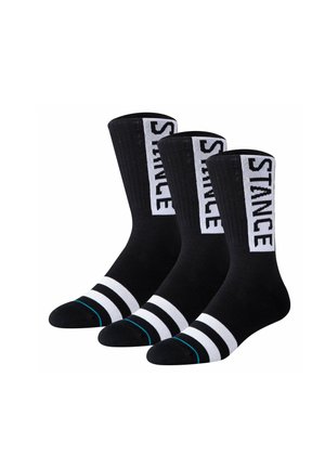 Drei schwarze Crew-Socken mit weißem "STANCE"-Text vertikal an der Seite und weißen Streifen nahe den Zehen, nebeneinander dargestellt.