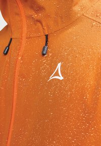 Helle orange wasserdichte Jacke mit Wassertropfen auf der Oberfläche und sichtbaren Kapuzenzugbändern.