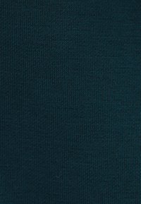 Tessuto a maglia turchese con una fine trama e un motivo uniforme, che mostra un colore costante e punti delicatamente arrotondati in tutto il tessuto.