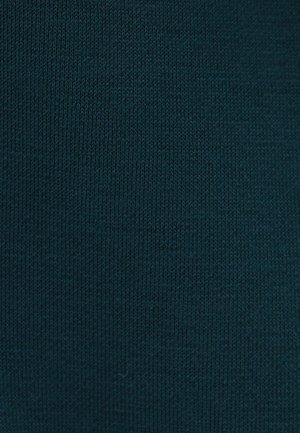 Teal neulekangas, jossa on hieno rakenne ja tasainen kuosi, esittäen yhdenmukaista väriä ja pehmeästi pyöristyneitä ompeleita koko ajan.