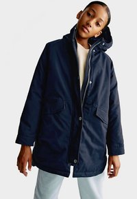 Marineblauwe parka met een ritssluiting aan de voorkant, twee grote zakken aan de voorkant en een verstelbare capuchon, gemaakt van een gladde, duurzame stof.